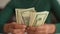 Close-up top view shot of unrecognizable African woman counting dollar bills. Closeup of black female hands count money