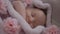 Close-up top view sleeping infant girl lying in cozy bed with pink flowers. Cute Caucasian baby with closed eyes