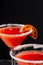 Close-up top view of two glasses of blood orange cocktail with sugar, selective focus, black background, vertical