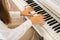 Close-up top view of unrecognizable musician female pianist playing gentle music on white classical piano in light