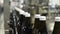 Close-up of the tops of glass water bottles moving on a conveyor in the shop. Production of drinking water at the food industry pl