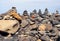 Close up of towers of stacked pebbles and colored stones in a large arrangement on a black sand beach with blue sky