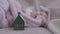 Close-up toy house on cozy bed with blurred innocent baby girl sleeping at background. Newborn Caucasian child enjoying