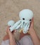 Close-up toy octopus in the hands of a young girl. In the frame is a large knitted toy octopus in the hands of an