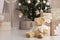 Close-up toy Teddy bear near the mountain of gifts packed in craft paper on a blurred background of a decorated Christmas tree,