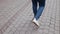 Close-up tracking shot of the legs of a man in white sneakers and a jeans walking confidently forward at the sidewalk on Tel Aviv