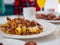 Close up of traditional American breakfast plate of potatoes, sausage, bacon on a dining table with full breakfast