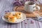 Close-up of traditional British scones dessert and a cookie on a plate with a teacup and flower blurred background. Space for text