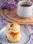 Close-up of traditional British scones dessert on a plate with a teacup and flower blurred background. Space for text.