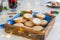 Close up traditional english festive pastry mince pies on wooden tray with blue napkin with blurred mulled wine drinks and lights