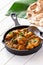 Close up traditional Indian butter chicken curry and lemon served with chapati bread on iron cast