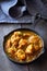 Close up traditional Indian butter chicken curry and lemon served with chapati bread in iron-cast. Wooden background.