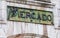 Close-up of traditional market sign Abastos, in Spanish. In oxidized bronze, with green and ocher tones