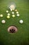 Close up of training golf balls spilled on the playground close to the hole, sport concept