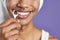 Close-up transgender man with dental floss smiling on purple background. Afroamerican trans gender