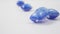 Close-up of transparent capsules with blue detergent falling on a white background.