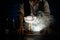 Close-up of transparent glass with large piece of ice standing on smoky bar counter