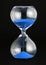 Close-up of a transparent hourglass with blue sand