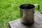 Close-up of travel metal mug with coffee or tea on wood table.