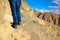 Close-up of traveler`s feet walking uphill on mountain and sand dune over blue sky