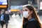 Close up of traveler woman wearing surgical mask at the airport. Worried young woman looking timetables of departures arrivals