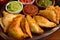 Close-up of a tray of assorted empanadas with different fillings and a side dish of fresh salsa and guacamole