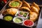 Close-up of a tray of assorted empanadas with different fillings and a side dish of fresh salsa and guacamole