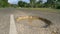 CLOSE UP: Tropical sun shines on large pothole in the middle of decaying road.