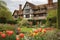 close-up of tudor house exterior, with manicured gardens and blooming flowers