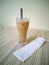 Close up on a tumbler glass full of iced coffee with a reusable metal drinking straw.