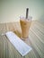 Close up on a tumbler glass full of iced coffee with a reusable metal drinking straw.