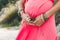 Close up of tummy of pregnant woman wearing long red dress outdo