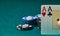 close-up of two aces held in one hand on the green game mat on the right side of the image to leave place for editing, poker chips