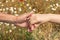 Close-up of two adult hands holding each other on a sunny day in nature