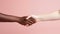 Close-up of two african american women shaking hands on pink background. hands of different persons