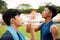 Close up two Asian teenagers drinking water from bottle after run in park