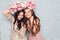 Close-up of two beautiful girls stand in a studio,who play silly with circlets of flowers on their heads. They wear