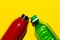 Close-up of two bottles. Steel reusable thermo water bottle and plastic disposable bottle. Isolated on yellow background.