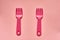 Close-up of two childish plastic pink forks on a pale pink background. Dishes for a picnic