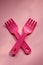 Close-up of two childish plastic pink forks on a pale pink background. Dishes for a picnic
