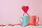 Close up of Two cups and heartshaped lolipop or hard candy on table. pink background. Place for text. copyspace. St. Valentine`s