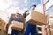 Close-up Of Two Delivery Men Carrying Cardboard Box