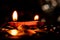 Close-up of two earthen lamps with flames, and shining coins below. Diwali and Dhan-teras concept