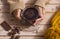 Close-up of two female human hands  holding a dark chocolate cup, creamy and thick. Wooden table as background and yellow wool cap