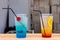 Close up of two fruity cocktails in transparent disposable glasses with straws for sale at the street food festival