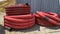 CLOSE UP: Two large coils of plastic conduits lay near a busy construction site.