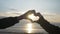 Close up of two lovers hand making a heart shape on a sunrise beach in slow motion -