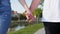 Close up of two lovers joining hands. Detail silhouette of man and woman holding hands and walking in the park. Couple