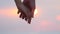 Close up of two lovers joining hands. Man and woman holding hands over the sunset blur background. Couple trust, Love