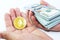 Close-up of two male hands of a Caucasian young man, on one side a stack of dollars, on the other an Ethereum coin.